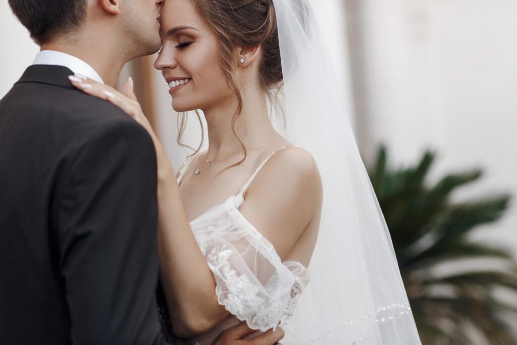 Smiling bride and groom holding each other in love. Flawless wedding makeup